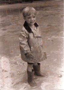 Middle Man as a little man, in his favorite red boots, his dad's old rain jacket and a mud puddle.